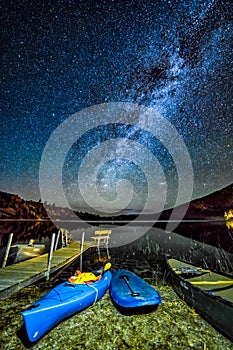 Photo of pier with boats around the water under night sky full of stars