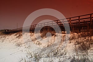 Photo of a pier jutting out over the sandy beach. photo
