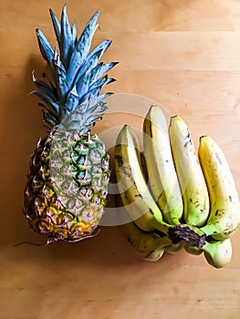 Photo of pineapple and bunch of bananas on the table