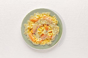 A photo of a plate of smoked salmon with bowtie pasta. Farfalle with salmon and a cream sauce, shot from above on a