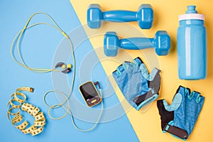 Photo of player, dumbbells, bottle of water, centimeter tape, gloves on blue and yellow background