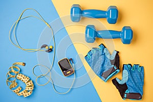 Photo of player, dumbbells, bottle of water, centimeter tape, gloves on blue and yellow background