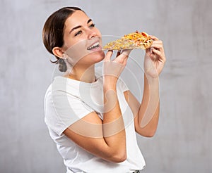 Photo of pleased young woman biting a piece of pizza