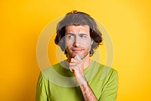 Photo of ponderous smart guy finger chin look side empty space wear green t-shirt isolated yellow color background