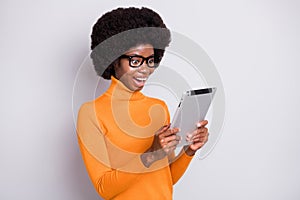 Photo portrait of amazed afro american woman holding tablet in two hands isolated on clear grey colored background