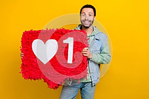 Photo portrait of attractive young guy hold red heart pinata influencer dressed stylish khaki garment isolated on yellow