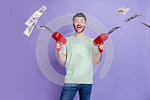 Photo portrait of attractive young guy wasting money gun shooting lottery wear trendy gray outfit isolated on violet