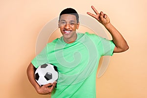 Photo portrait of attractive young man show v-sign football play dessert food wear trendy green clothes isolated on