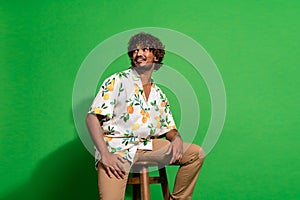 Photo portrait of attractive young man sit chair look empty space wear trendy citrus print clothes isolated on green