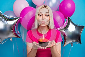 Photo portrait of attractive young woman air balloons cupcake blow candle dressed stylish pink clothes isolated on blue