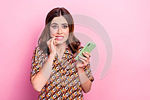 Photo portrait of attractive young woman bite nail hold telephone scared wear trendy print clothes isolated on pink