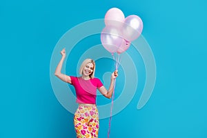 Photo portrait of attractive young woman hold dancing air balloons dressed stylish pink clothes isolated on blue color