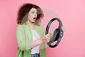 Photo portrait of attractive young woman hold steering wheel nervous wear trendy green clothes isolated on pink color