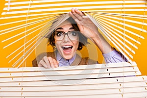 Photo portrait of attractive young woman peek jalousie excited impressed dressed retro office clothes isolated on yellow