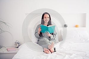 Photo portrait of attractive young woman sit bed read interesting book dressed stylish gray pajama  on white