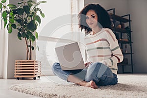 Photo portrait of attractive young woman sit floor netbook crossed legs dressed casual clothes cozy day light home
