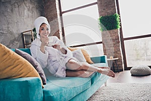 Photo portrait of attractive young woman sit sofa drink tea head wrapped towel dressed bath robe home interior enjoy