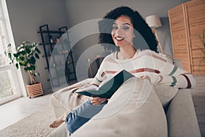 Photo portrait of attractive young woman sit sofa read book smile dressed casual clothes cozy day light home interior