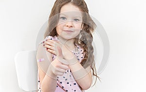 Photo portrait baby girl got vaccine from covid 19 smiling pointing finger recommending 