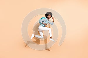 Photo portrait of brunette african american girl running jumping up wearing casual clothes cyan bag isolated on pastel