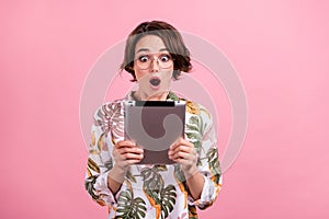 Photo portrait business woman in glasses keeping tablet shocked amazed isolated pastel pink color background