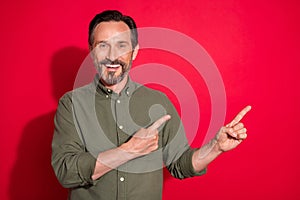 Photo portrait businessman wearing green shirt pointing empty space isolated bright red color background