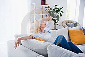 Photo portrait of charming retired woman sit sofa have rest enjoy weekend closed eyes stylish home decor living room