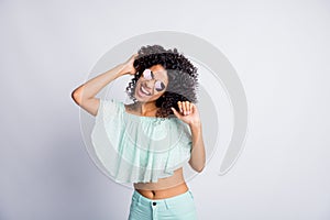 Photo portrait of cheerful mulatto brunette girl curly hair in sunglass dancing in summer clothes isolated on grey color