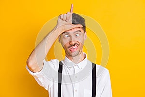 Photo portrait of comic silly ridiculous man showing looser sign abusing fooling grimacing isolated on bright yellow
