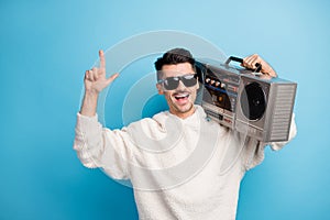 Photo portrait of cool dude with stubble pointing finger up holding boombox on shoulder isolated on pastel blue colored