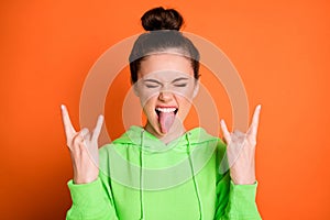 Photo portrait of crazy girl showing tongue two rock goat signs isolated on vivid orange colored background