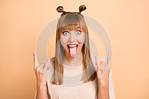 Photo portrait of crazy girl staring showing tongue horns rock roll isolated on pastel beige color background