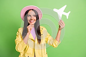 Photo portrait of curiousl woman smiling thinking about trip plane holidays in pink hat isolated on vivid green color