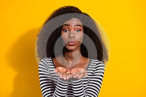 Photo portrait of curly woman in casual clothes sending air kiss with pouted lips isolated vibrant yellow color