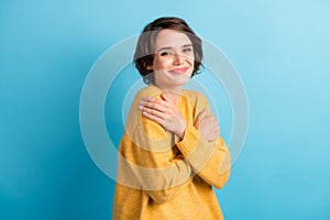 Photo portrait of cute girl embracing hugging herself wearing warm yellow jumper isolated on vibrant blue color
