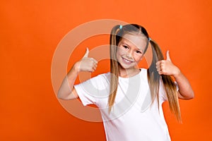 Photo portrait of cute little lady show double thumb up good quality wear trendy white garment isolated on orange color