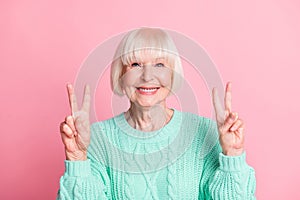 Photo portrait of cute nice senior woman in teal sweater blonde hair showing v-sign isolated on pastel pink color