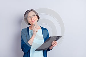 Photo portrait of elder business woman looking empty space keeping pen clipboard isolated on grey color background