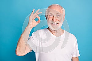 Photo portrait of elderly man showing ok-sign isolated on pastel blue colored background