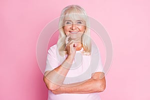 Photo portrait of elderly woman thinking touching face cheek with finger isolated on pastel pink colored background