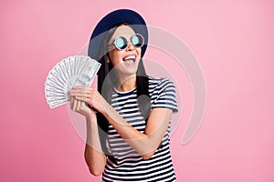 Photo portrait of excited woman with open mouth showing money fan isolated on pastel pink colored background
