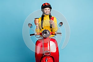 Photo portrait female driver sitting on motorcycle drinking coffee browsing internet smartphone isolated vibrant blue