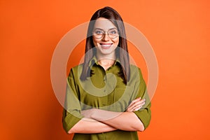Photo portrait of female freelancer smiling with folded hands wearing glasses green shirt isolated on bright orange