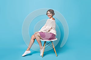 Photo portrait full body side profile view of girl sitting on chair isolated on pastel blue colored background