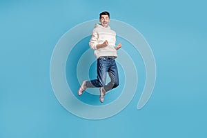 Photo portrait full body view of funny celebrating man jumping up wearing woolen hoodie isolated on pastel blue colored