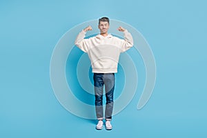 Photo portrait full body view of funny man flexing biceps wearing woolen hoodie isolated on pastel blue colored