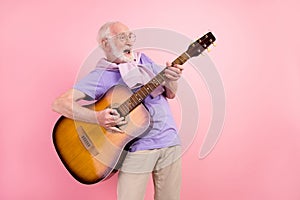 Photo portrait of funky happy grandpa playing guitar smiling like rock star isolated on pastel pink color background