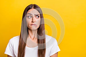Photo portrait girl brown hair white t-shirt looking copyspace biting lip isolated vivid yellow color background