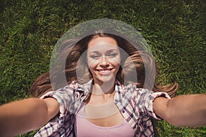 Photo portrait of girl chilling relaxing laying on grass taking selfie smiling in plaid shirt