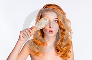 Photo portrait of girl with curly red hair keeping covered eye hairbrush doing haircare treatment with pouted lips